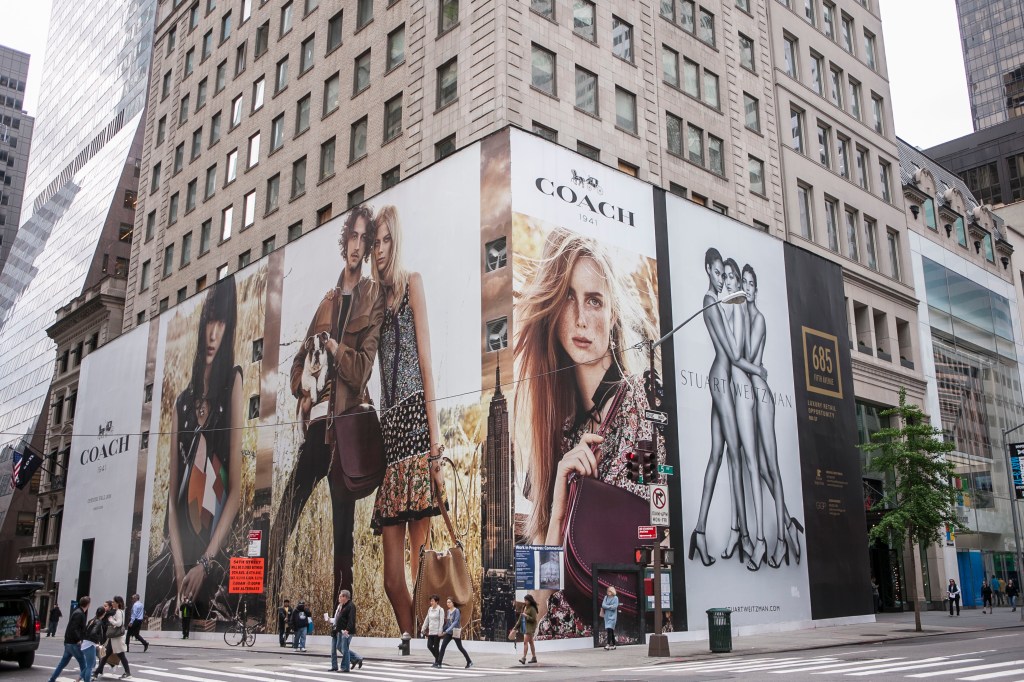 The front of the Coach store at 685 5th Ave, NY, with a large mural featuring Edie Campbell, Lexi Boling, Gigi Hadid, Joan Smalls, Lily Aldridge, Helena Wong and Tom Mandrake.